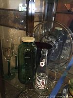 Photo showing the complete lot including four champagne flutes, green water jar with metal lid, clear glass platter, red hand-blown glass vase, and Brownie bottle.