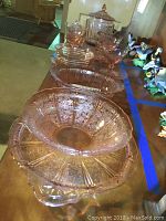 Overview of multiple pink Depression Glass pieces shown on table