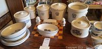 Full display of Pfaltzgraff set on wooden table showing four cannisters, large crock, butter dish, salt and pepper shakers, and multiple serving bowls and plates.