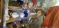 Front view of white wire snap-together rack holding dishes and decorative items on wooden shelves.