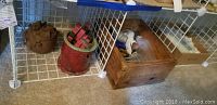 Overview of the items on a wire rack including pottery pieces, wooden box with glass bottles, and a small red container with napkin rings.