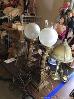 Photo showing the two brass column lamps with frosted etched glass globes, smaller lamp with painted floral shade and candle holders with clear chimneys.