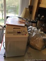 Hitachi HB-B101 bread maker on table with cookbooks on top