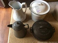 Four items shown together: white porcelain pitcher with decorative handle, white enameled pot with lid, gray marbled enameled coffee pot with lid, black Wagner Ware cast iron roaster No. 8 with lid
