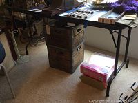 Full side view of the folding table showing woodgrain top surface and black metal legs, with surrounding furniture for size reference.