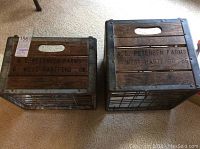Two wood and metal crates with stencil text 'A.C. Petersen Farms' visible from top angle on carpeted floor.