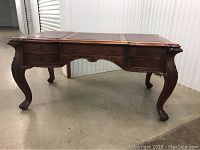 Full front view of carved wooden desk with leather inset surfaces