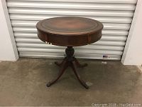 Full view of round wooden side table with a pedestal base with three legs.