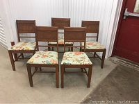 Set of five wooden dining chairs arranged in two rows, showing front view with floral upholstered seats and rectangular backrests.