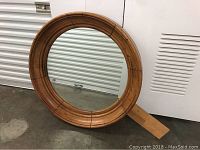 Full front view of round wooden framed mirror showing entire piece and removable attachment plank.