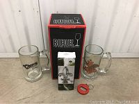 Photo showing beer mugs, Riedel decanter box, wine bottle stopper box and bottle opener key chain