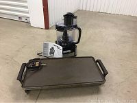 Hamilton Beach food processor and Toastmaster electric griddle on concrete floor, food processor manual included.