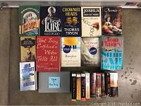 Books and audiobooks on CDs laid out on concrete floor. Titles include novels and complete audiobook sets in CD cases.