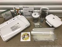 Full view of FoodSaver vacuum sealer machine, vacuum bags, container, grater, and manuals