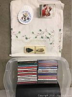 Christmas tablecloth folded with Christmas decorative soaps, paper coasters, and a Coca-Cola glass with Santa Claus image on top.