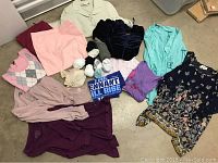 Overall lot of various women's clothing items including tops, sweaters, blouses, socks, pants in small and medium petite sizes.