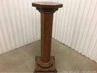 Front view of the wooden pedestal stand showing octagonal top and base with carved curved feet.