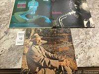 Three vintage jazz vinyl records displayed on a marble countertop showing album covers for The Horace Silver Quintet, Sam The Man Taylor, and The Essential Charlie Parker.
