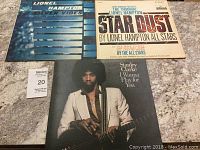 Three vintage vinyl records with album covers laid out on a surface: Lionel Hampton Silver Vibes and Stardust 2 record set and Stanley Clarke I Wanna Play for You album.