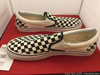 Side profile of Vans men's size 13 slip-on sneakers in black and white checkerboard pattern.