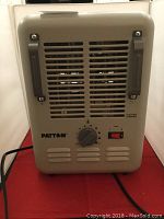 Front view of Patton electric heater showing control knob, switches, and handles on beige metal housing.