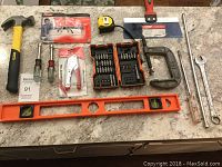 Overview of the tool set including hammer, screwdrivers, safety glasses, tape measure, putty knife, screwdriver bit set, C-clamp, spirit level, and wrenches.