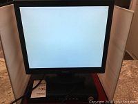 Monitor showing a blank white screen with cables connected, positioned on a granite surface.