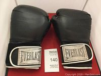 Front view of the Everlast boxing gloves showing the black exterior and Everlast logo on the wrist strap.