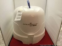 Closed view of the Gold N Hot 1200 hair dryer dome hood on a red surface showing the front label