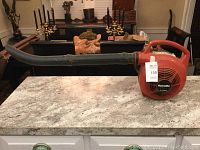 Side view of the full leaf blower showing the red casing, black air tube, and handle.