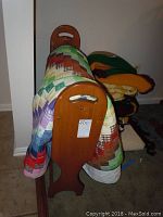 Wooden quilt rack with patchwork quilt and several folded crocheted and knitted blankets beside it.