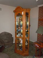 Full view of oak cabinet from front-left angle showing carved crown and interior shelves
