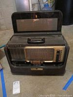 Front view of vintage Zenith Trans-Oceanic radio in black case showing tuning dial, control knobs, and buttons.