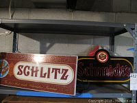 Both Schlitz and Schmidts beer signs displayed on a metal shelf, showing condition and size relation