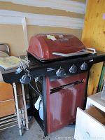 Full view of red Char Broil propane grill with three control knobs and side shelves, showing its overall condition and size.
