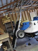 Side view of LoadRite branded aluminum jet ski trailer with black padded rails and single axle with tire.