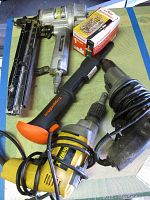 Photo showing the majority of tools including Hitachi nail gun, Ramset trigger shot, Black and Decker drill, DeWalt drywall screwdriver, and a box of Ramset nails.