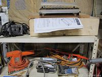 Photo showing the Black and Decker dual action sander, electrical cords, and other tools on shelf