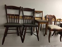 Multiple wooden chairs arranged side by side showing varying designs and upholstery.