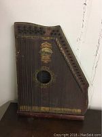 Front view of vintage American Mandolin Harp with painted emblem and strings across the front.