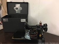 Front view of Singer sewing machine beside open black carrying case