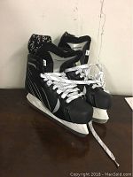 Pair of black and white Winwell NXT Windwell hockey skates displayed on a table against a white wall.