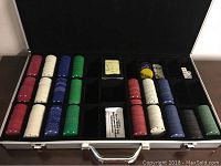 Poker chip set organized inside the carrying case showing various colored chips, dealer and blind buttons, playing cards and dice.