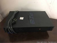 Top view of black Sony PlayStation 2 console with a power cord resting on top, showing cleanliness and branding on the surface.