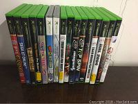 Front view of 14 Xbox video games in cases, titles visible on spines.