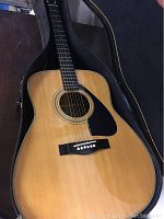 Yamaha FG-420 acoustic guitar inside the open case showing the natural wood top and black pickguard.