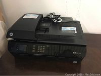 Front angle view of black HP OfficeJet 4630 with keypad and screen showing model info and power cord on top.