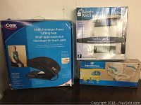 Photo showing Carex Uplift Premium Power Lifting Seat box, Weight Watchers Glass Body Analysis Scale box, and AquaSense Toilet Safety Rail box.