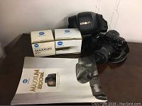 Minolta Maxxum 800si camera with lens attached, flash unit in case, boxes with lens and flash, and user manual.