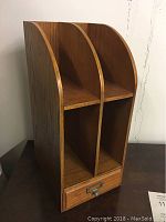 Front view of vintage wooden desk organizer showing three vertical compartments and drawer at the bottom with metal label holder.